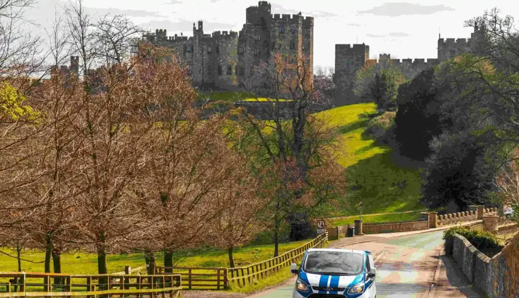 A car driving away from a castle on a hill