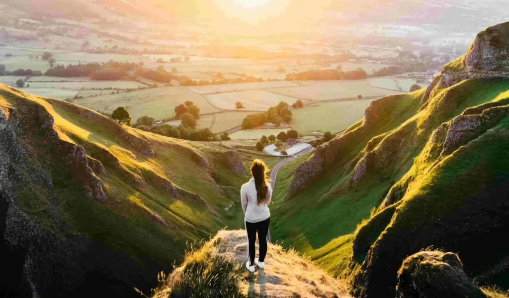 Woman standing between two hills at sunset