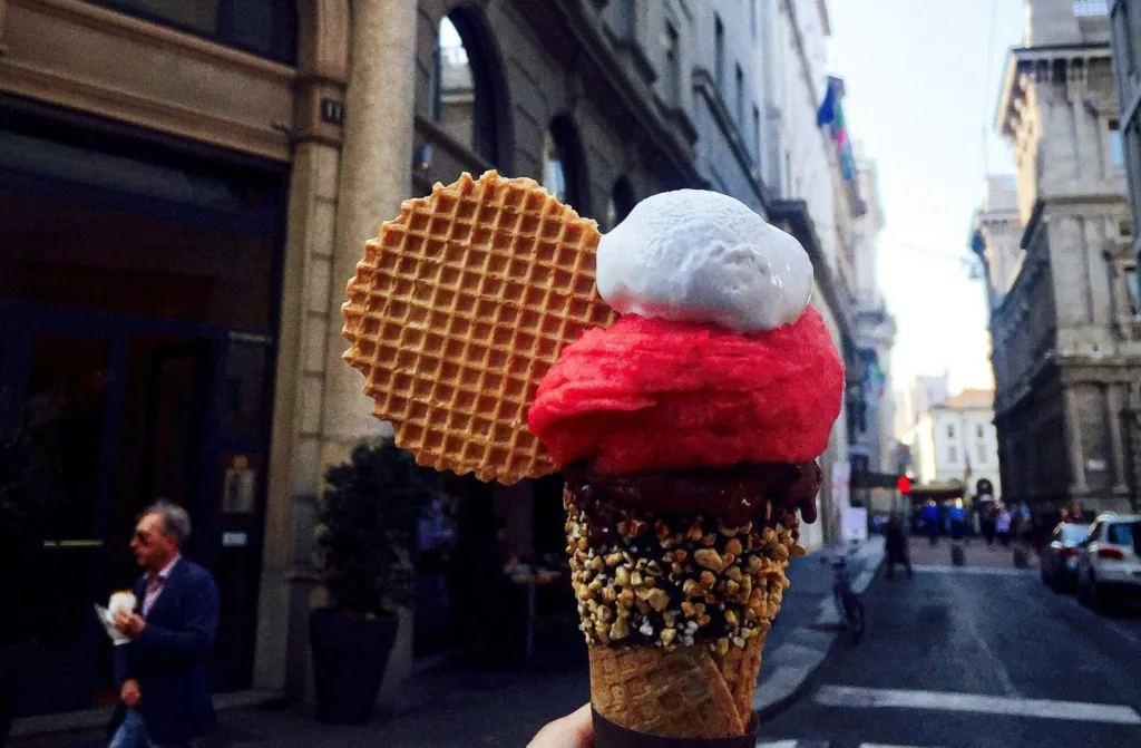 person holding an ice cream on a city street