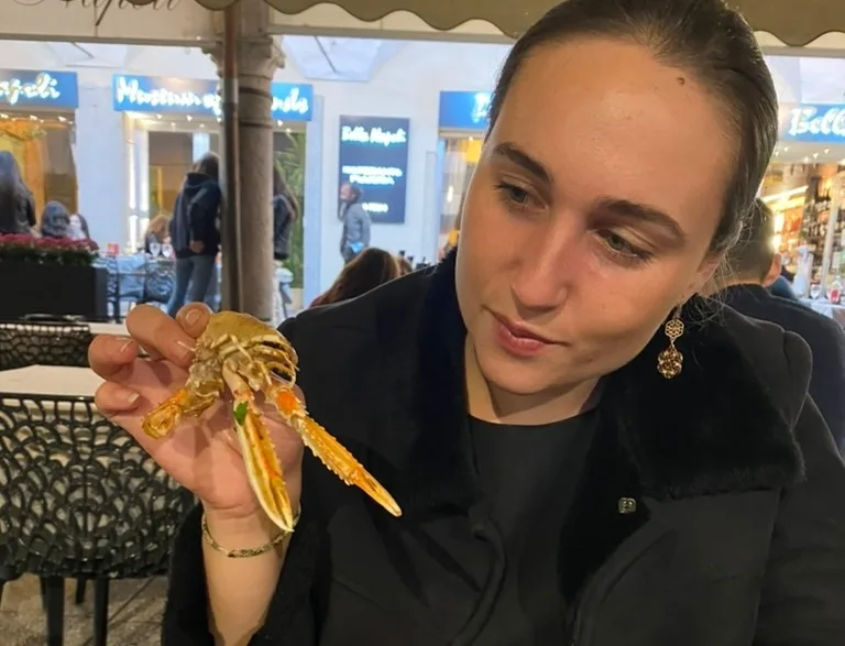 woman holding a crustacean at a restaurant outdoors